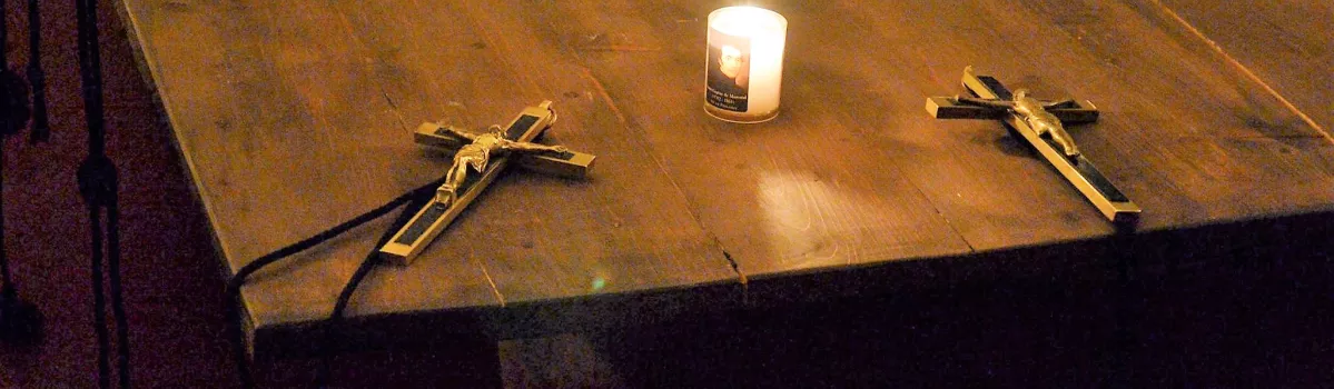 Kreuze, die auf einem Tisch um eine Kerze gruppiert liegen.